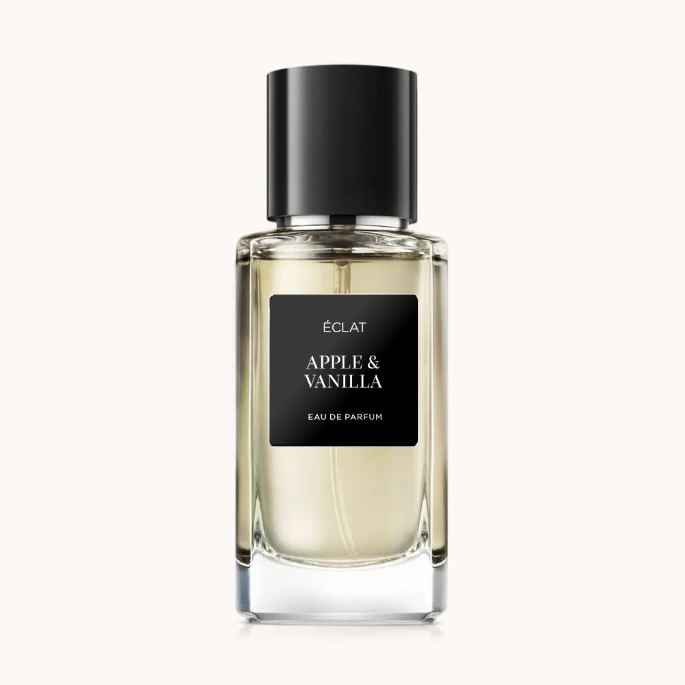 Flacon of the men's perfume dupe ÉCLAT Apple & Vanilla, an elegant transparent glass bottle with a black cylindrical magnetic cap and a black label. The label displays the brand name ÉCLAT, the name Apple & Vanilla, and the phrase “Eau de Parfum”.