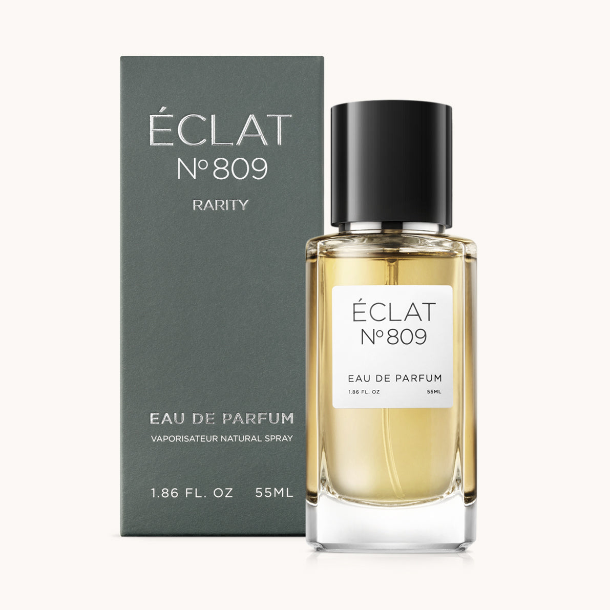 The ÉCLAT Ambery Cinnamon fragrance is presented in a clear glass bottle with a black cap, alongside its elegant green packaging.