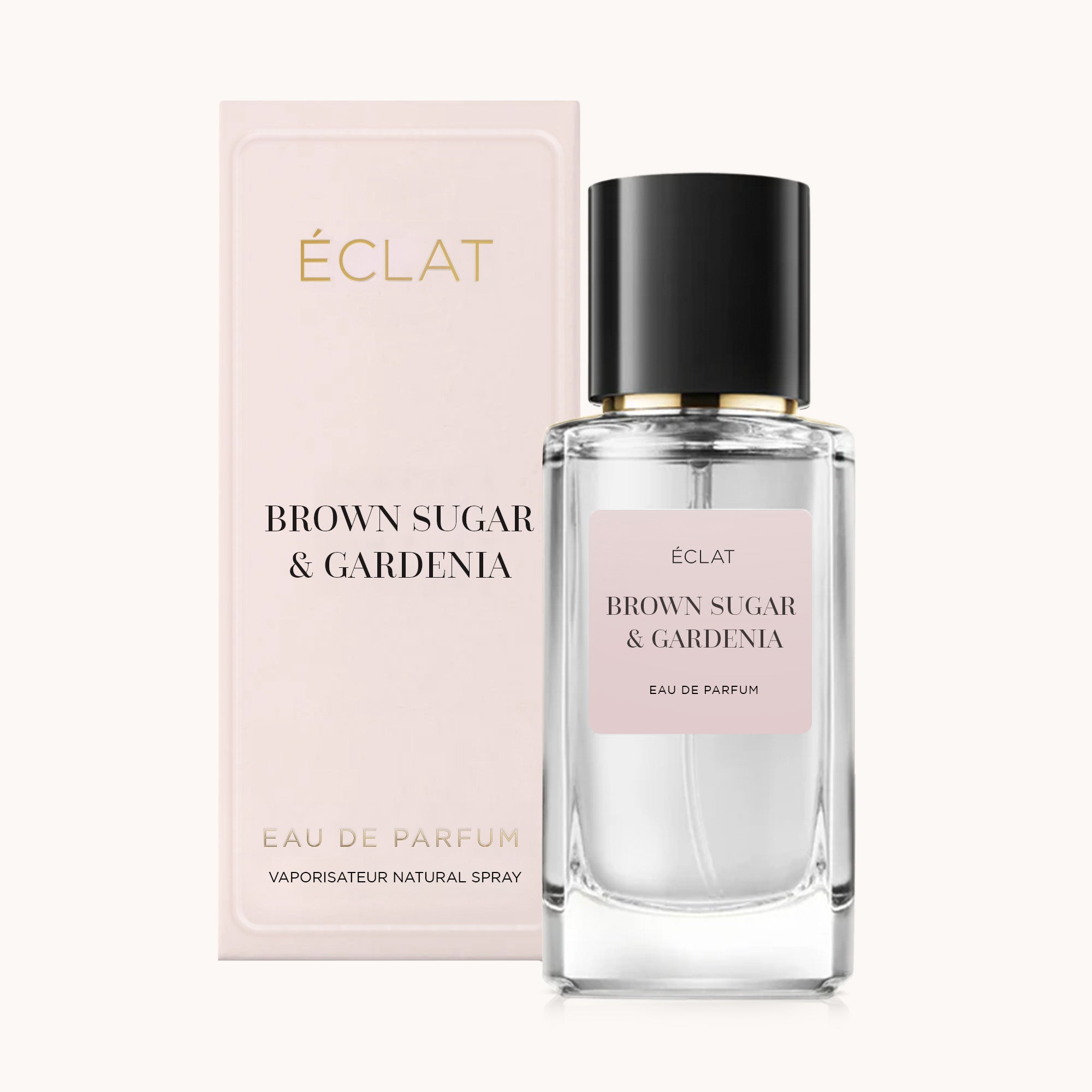 A faceted glass bottle of ÉCLAT Brown Sugar & Gardenia perfume with a black cap, next to a soft pink presentation box.