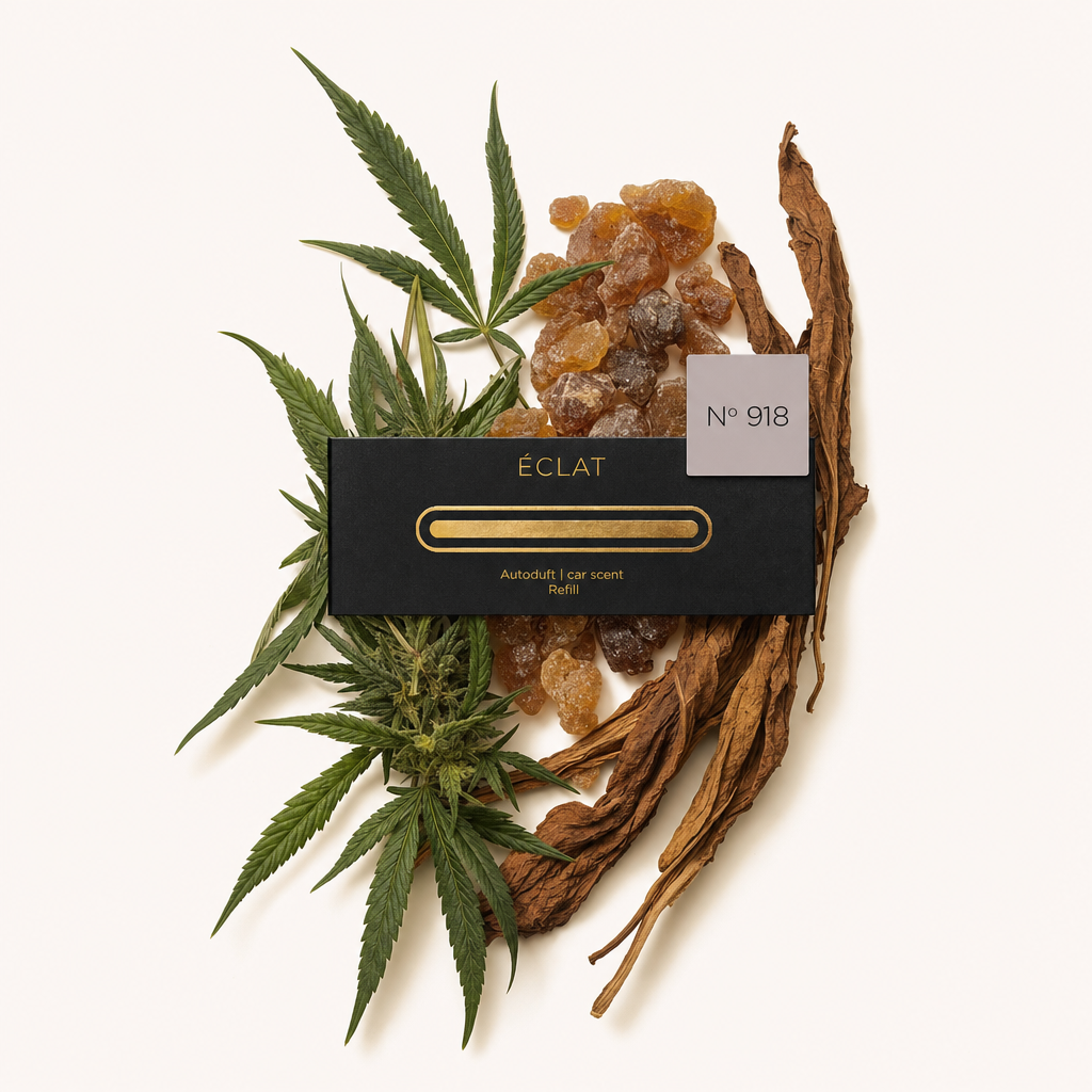 Un arreglo de hojas verdes, resina ámbar y tabaco marrón rodea una tapa negra de ÉCLAT con una etiqueta que dice No. 918.
