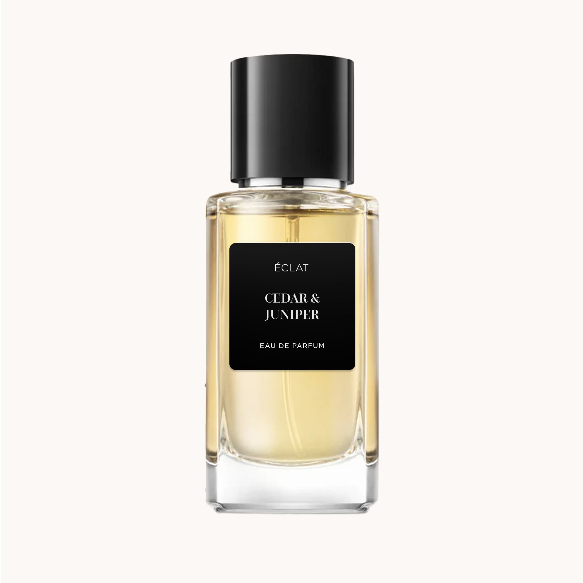 Um frasco de vidro facetado de ÉCLAT Cedar & Juniper com tampa e rótulo pretos, exibindo uma fragrância de tom dourado.