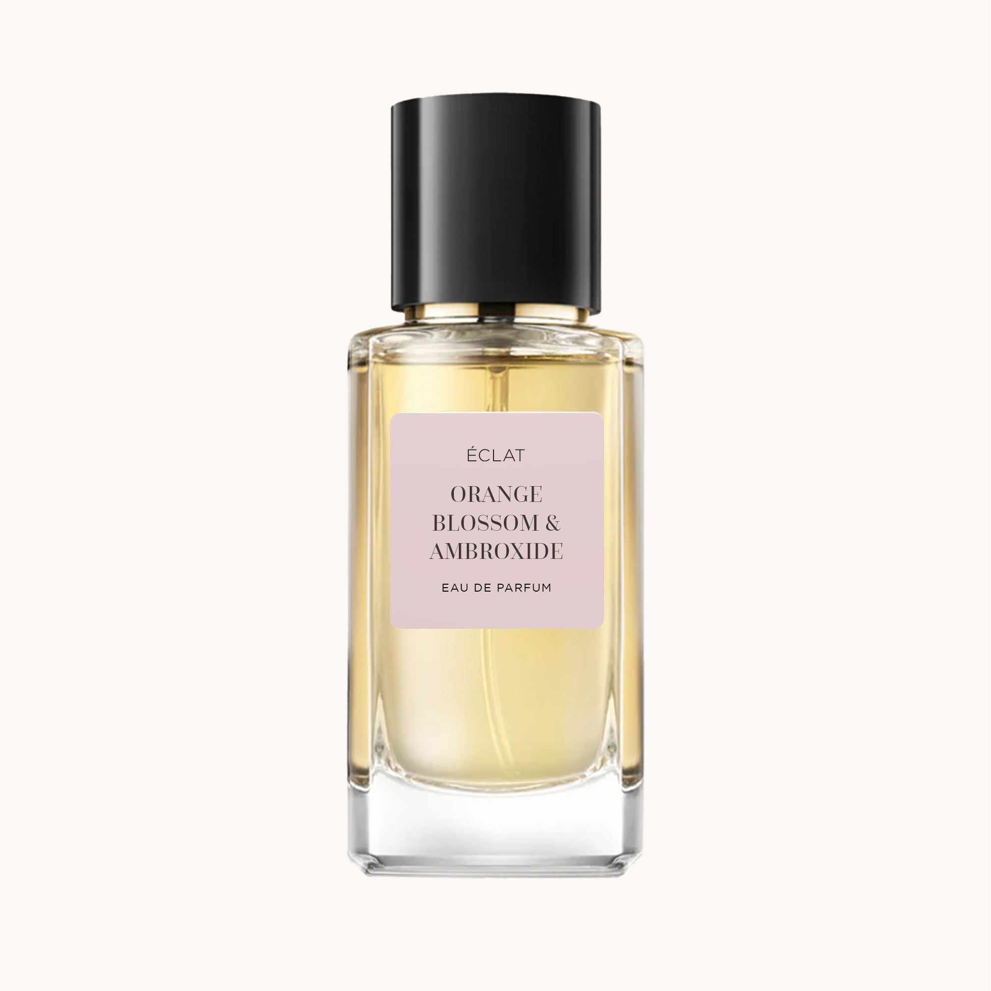 Faceted glass bottle of ÉCLAT Orange Blossom & Ambroxide with a black cap and a soft pink label.