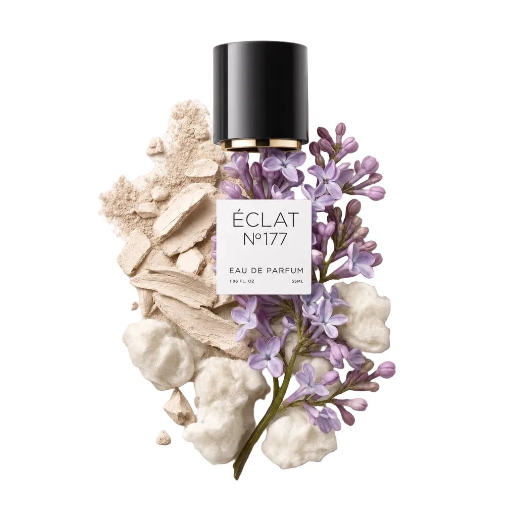 Een arrangement van lila bloemen met delicate paarse tinten, omgeven door zacht wit katoen en beige poederfragmenten. Bovenaan ligt een zwarte dop met gouden rand en ÉCLAT-label.
