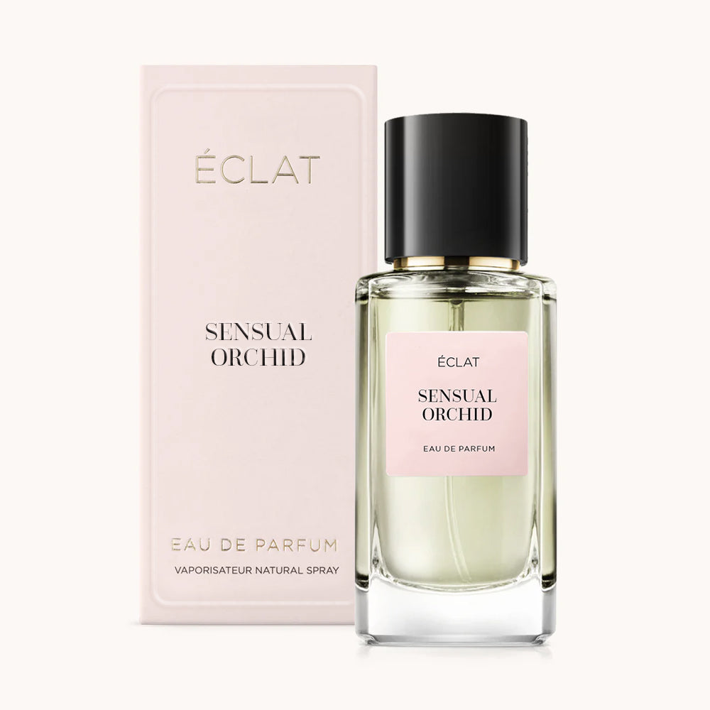 Un flacon en verre facetté avec un bouchon noir et une étiquette rose se tient à côté de son coffret de présentation rose pour ÉCLAT Sensual Orchid.