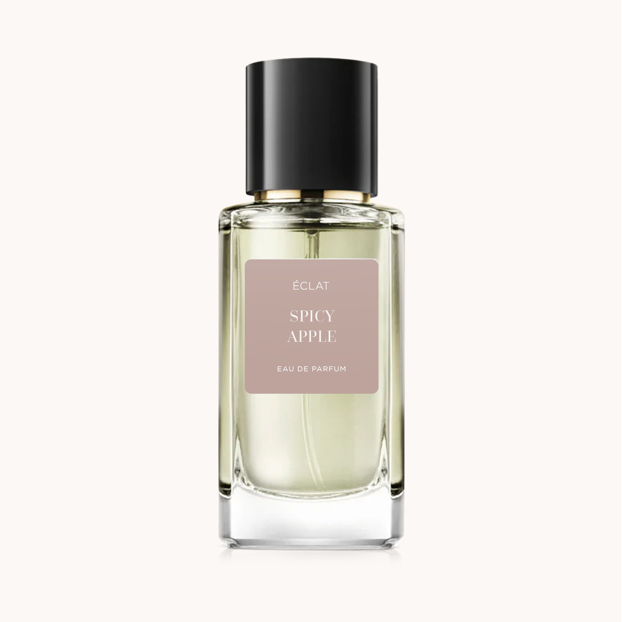 Faceted glass bottle of ÉCLAT Spicy Apple with a sleek black cap, featuring a matte label on a pale beige background.