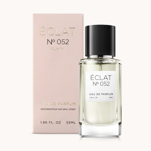 En fasetterad glasflaska av ÉCLAT Spicy Milk med svart lock, åtföljd av en mjukt rosa presentlåda.