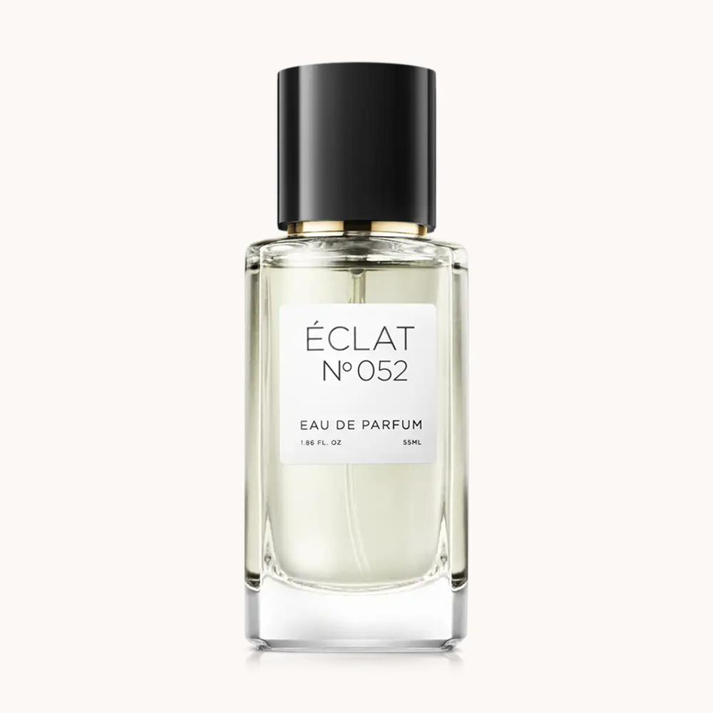 En facetterad glasflaska av ÉCLAT Spicy Milk med elegant svart lock och minimalistisk vit etikett.