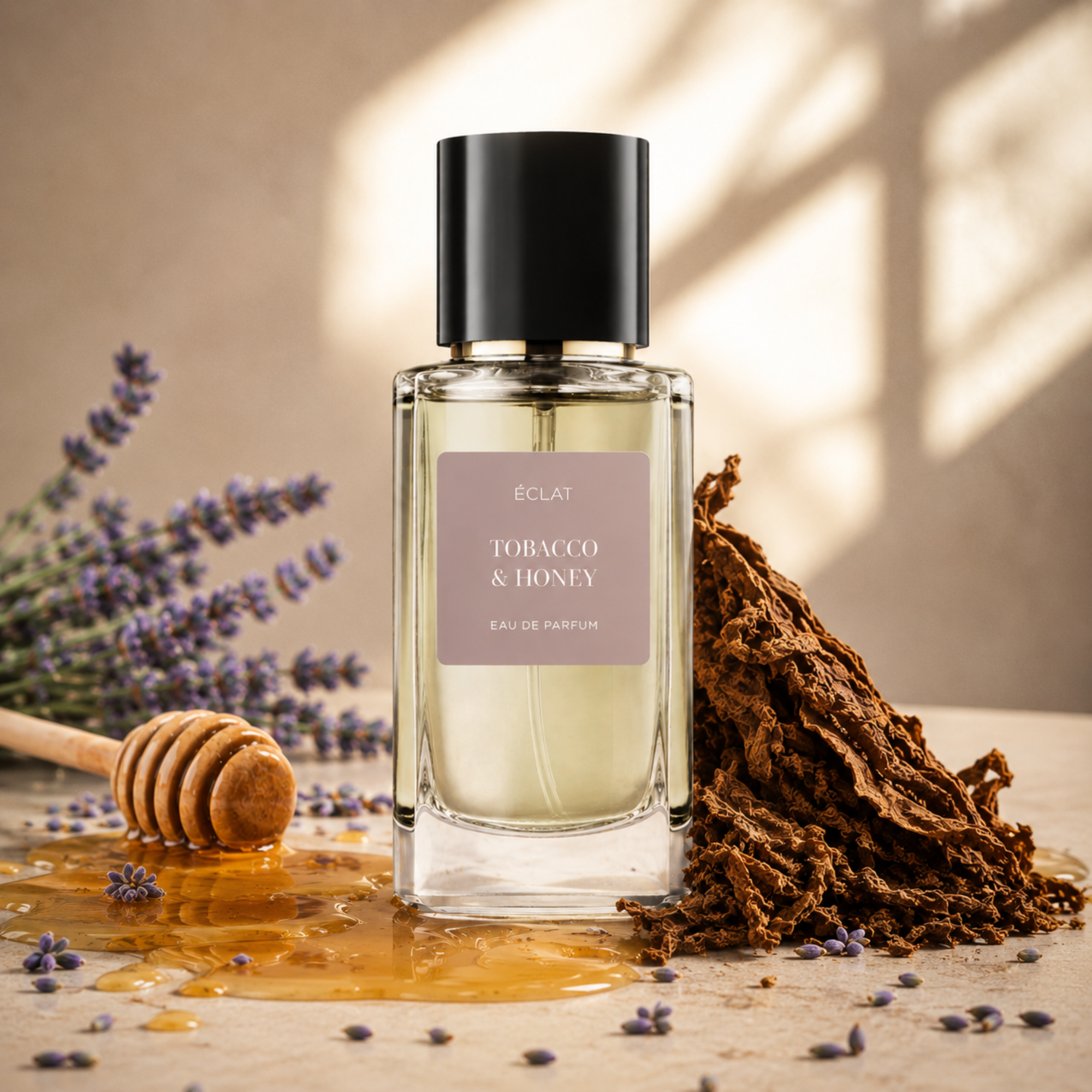 A faceted glass bottle of ÉCLAT Tobacco & Honey with a black cap, surrounded by honey, tobacco leaves, and lavender sprigs.