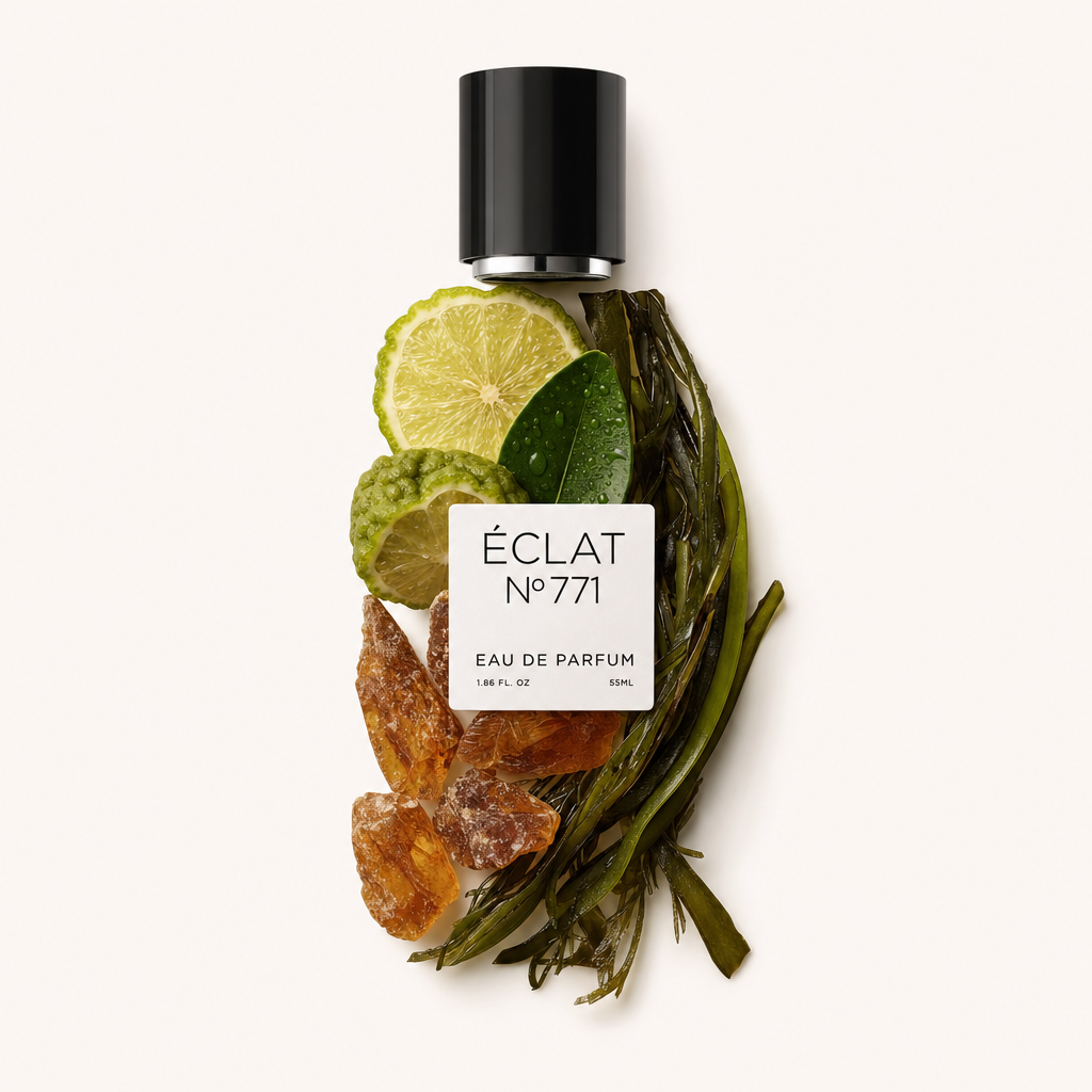 Une nature morte arrangée à la main des ingrédients de l'ÉCLAT Aquatic Ambroxide avec des tranches de citron vert, des feuilles d'olivier, des cristaux d'ambre et des algues, surmontée d'un capuchon noir et d'une étiquette.