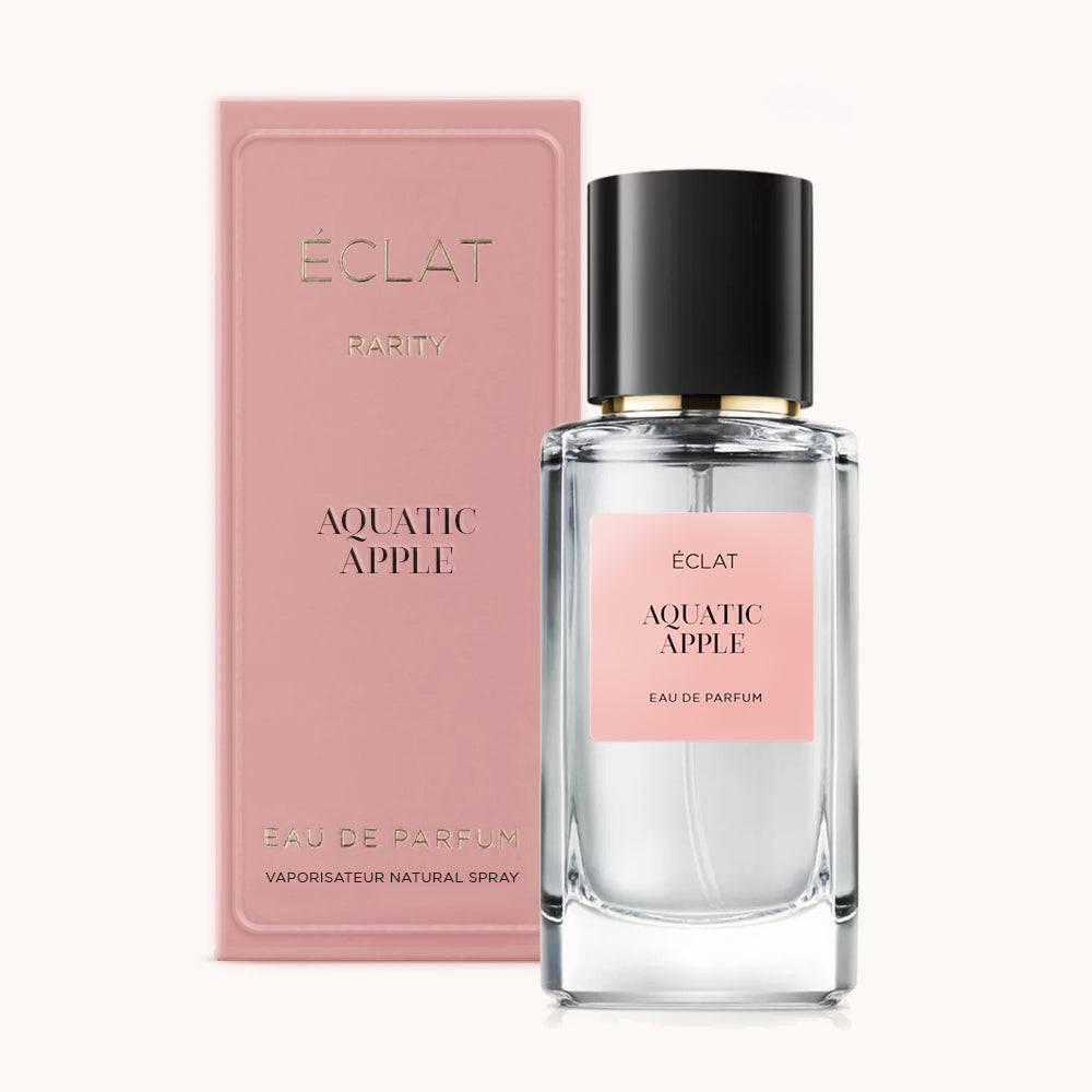 A faceted glass bottle of ÉCLAT Aquatic Apple with a black cap, accompanied by a pink box with elegant branding.