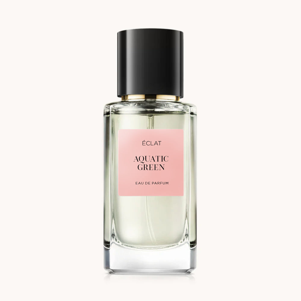 ÉCLAT Aquatic Green perfume in a faceted glass bottle with a pink label and a black cap.