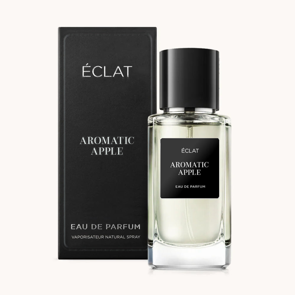 A clear glass bottle of ÉCLAT Aromatic Apple with a black label and cap, accompanied by a matching elegant black box.