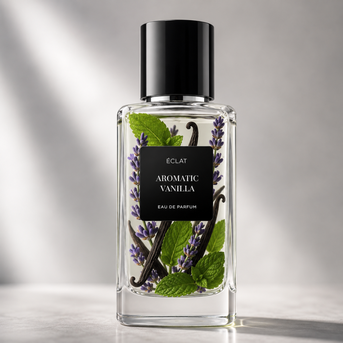 Elegant glass bottle of ÉCLAT Aromatic Vanilla, displaying a black label with lavender sprigs, vanilla pods, and mint leaves inside.