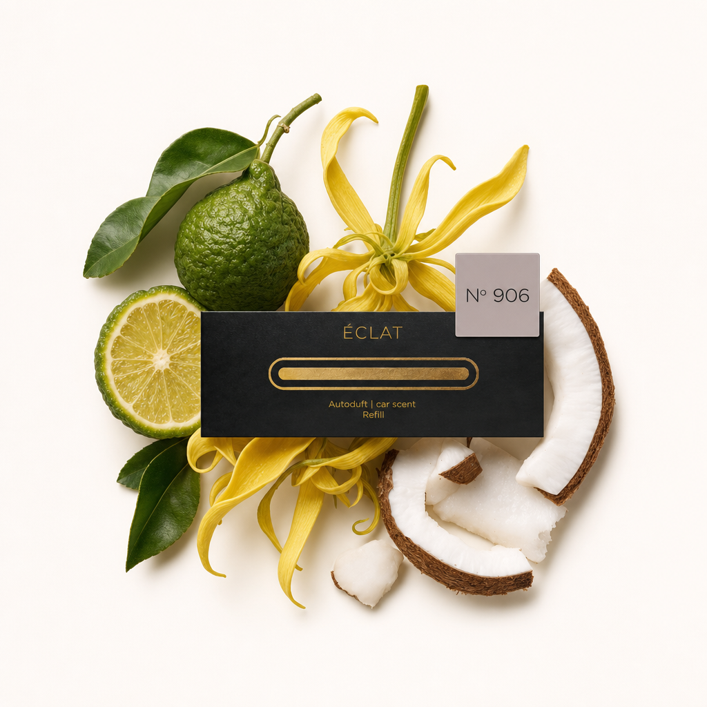 Un arreglo de bergamota, flores de ylang-ylang y secciones de coco rodea una tapa de fragancia para automóvil negra de ÉCLAT con etiqueta.