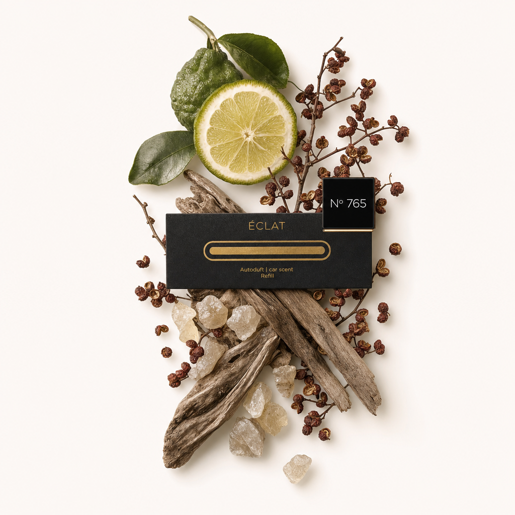 Un arrangement de tranche de citron, feuilles de lime, poivres séchés, morceaux de résine et bois flotté autour d'un bouchon noir ÉCLAT avec étiquette.