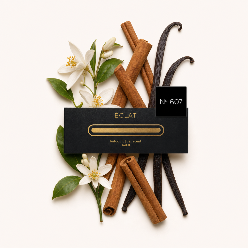Uma composição de flor de laranjeira, paus de canela e vagens de baunilha envolve a tampa preta ÉCLAT No. 607 com etiqueta.