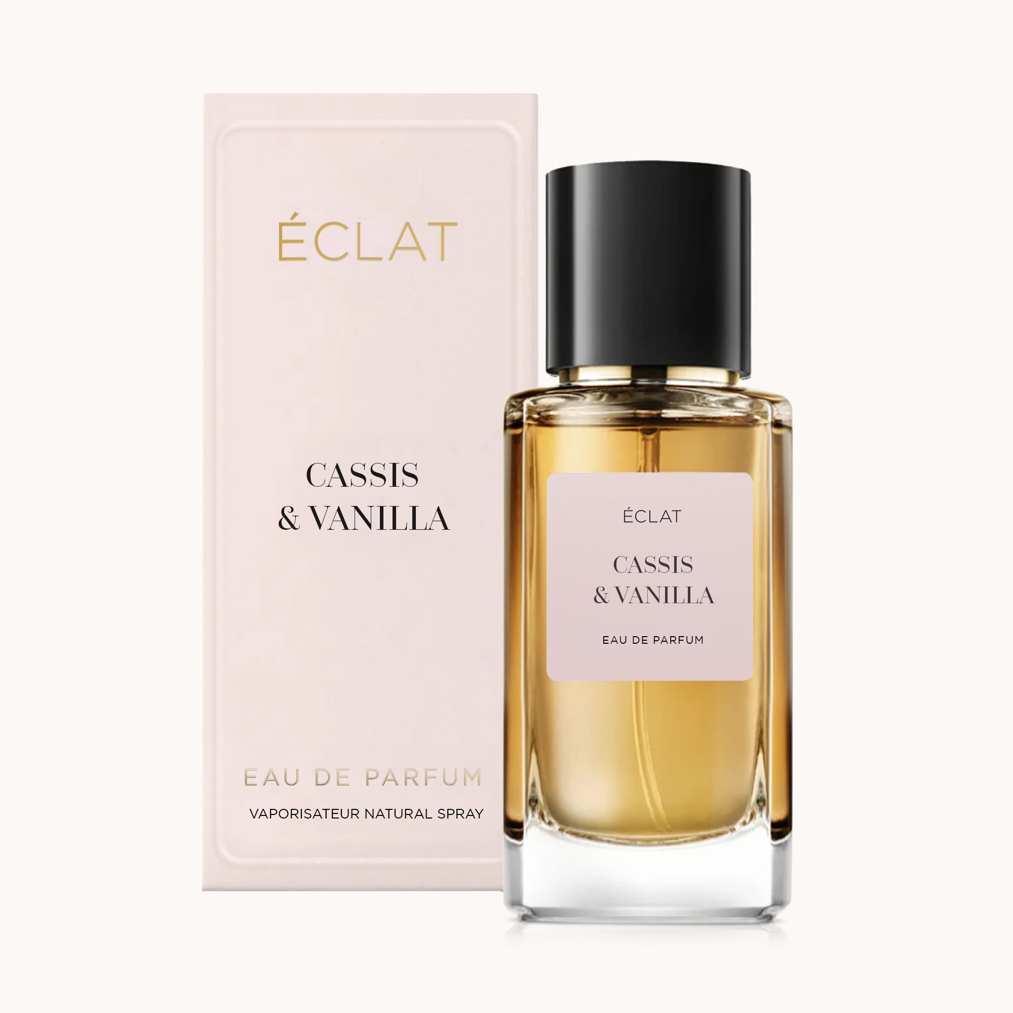 Le parfum ÉCLAT Cassis & Vanilla présente un flacon en verre facetté avec un bouchon noir, accompagné d'une boîte rose pastel.