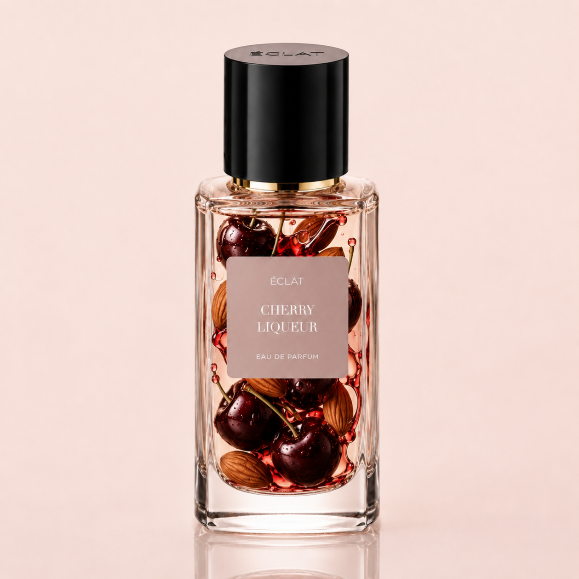 Faceted glass bottle of ÉCLAT Cherry Liqueur eau de parfum with a black cap and a label depicting cherries and almonds.