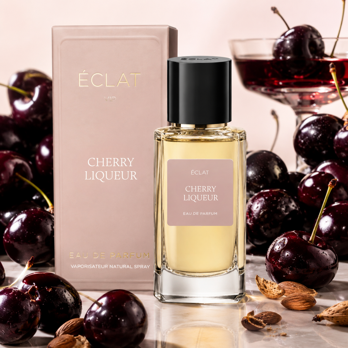 The image shows ÉCLAT Cherry Liqueur perfume with a faceted glass bottle and black cap, next to a pink box and fresh cherries.