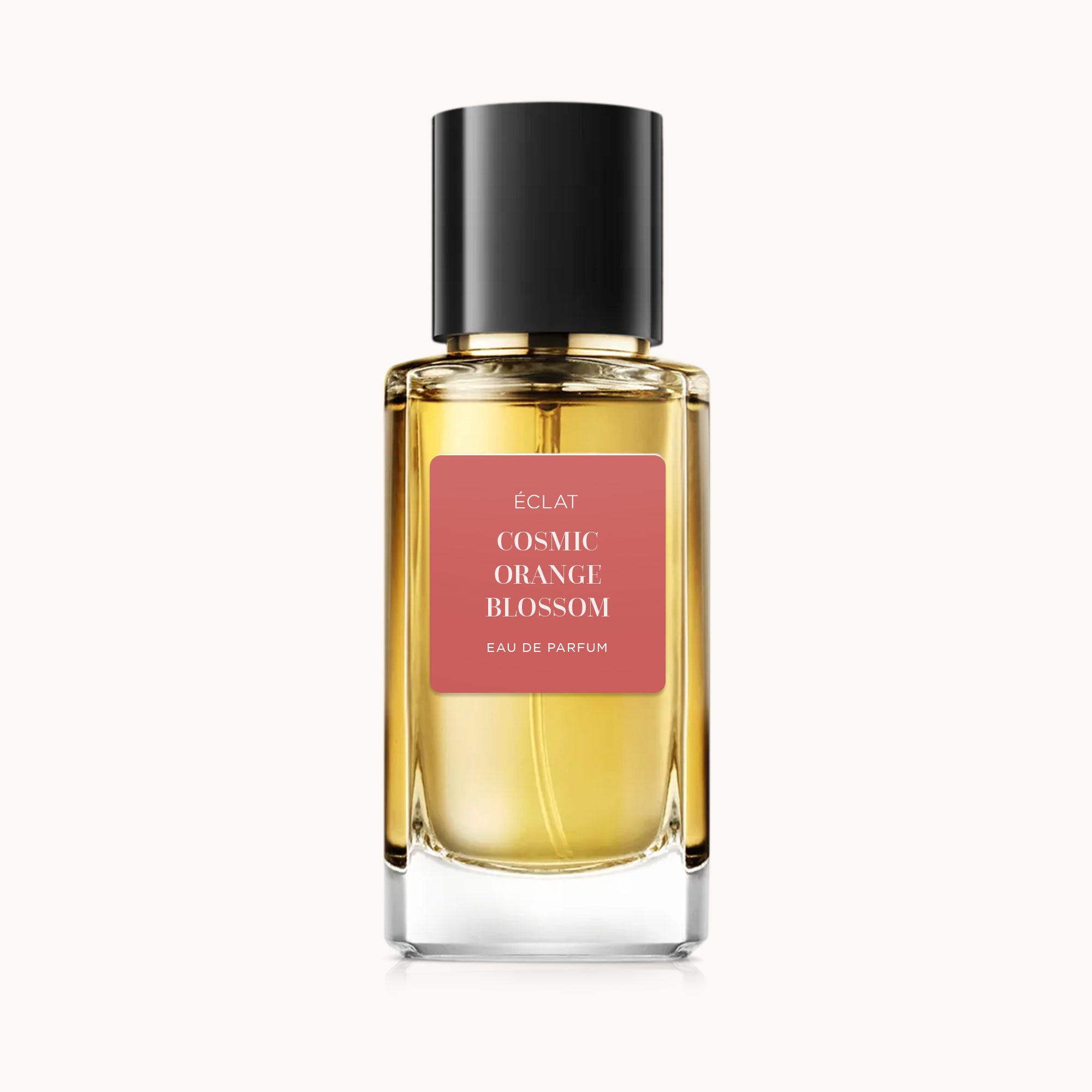 A faceted glass flacon containing ÉCLAT Cosmic Orange Blossom, featuring a coral-colored label and a glossy black cap.