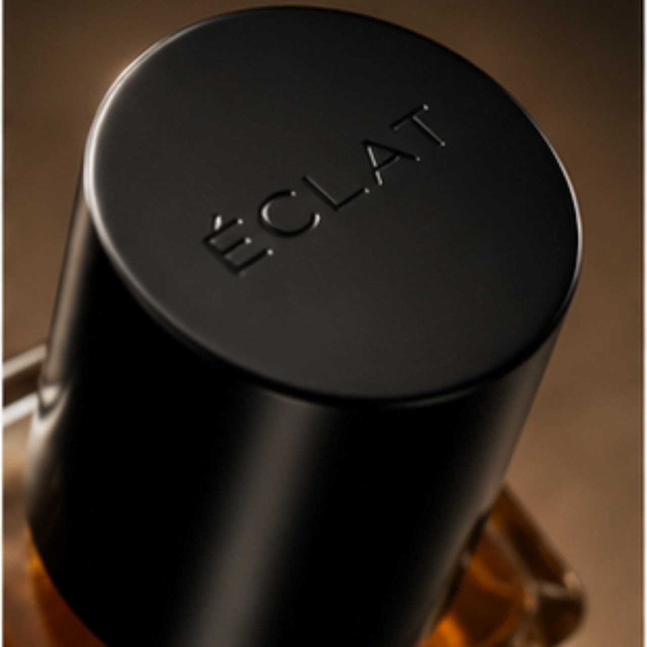 A sleek black cap engraved with ÉCLAT sits atop a faceted glass bottle containing a warm amber liquid.