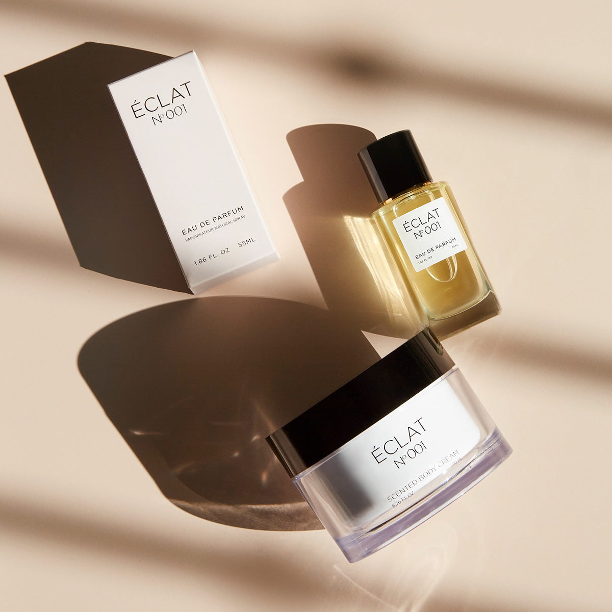 ÉCLAT Floral Aldehydes perfume and scented body cream with a black cap next to a white box on a light surface.
