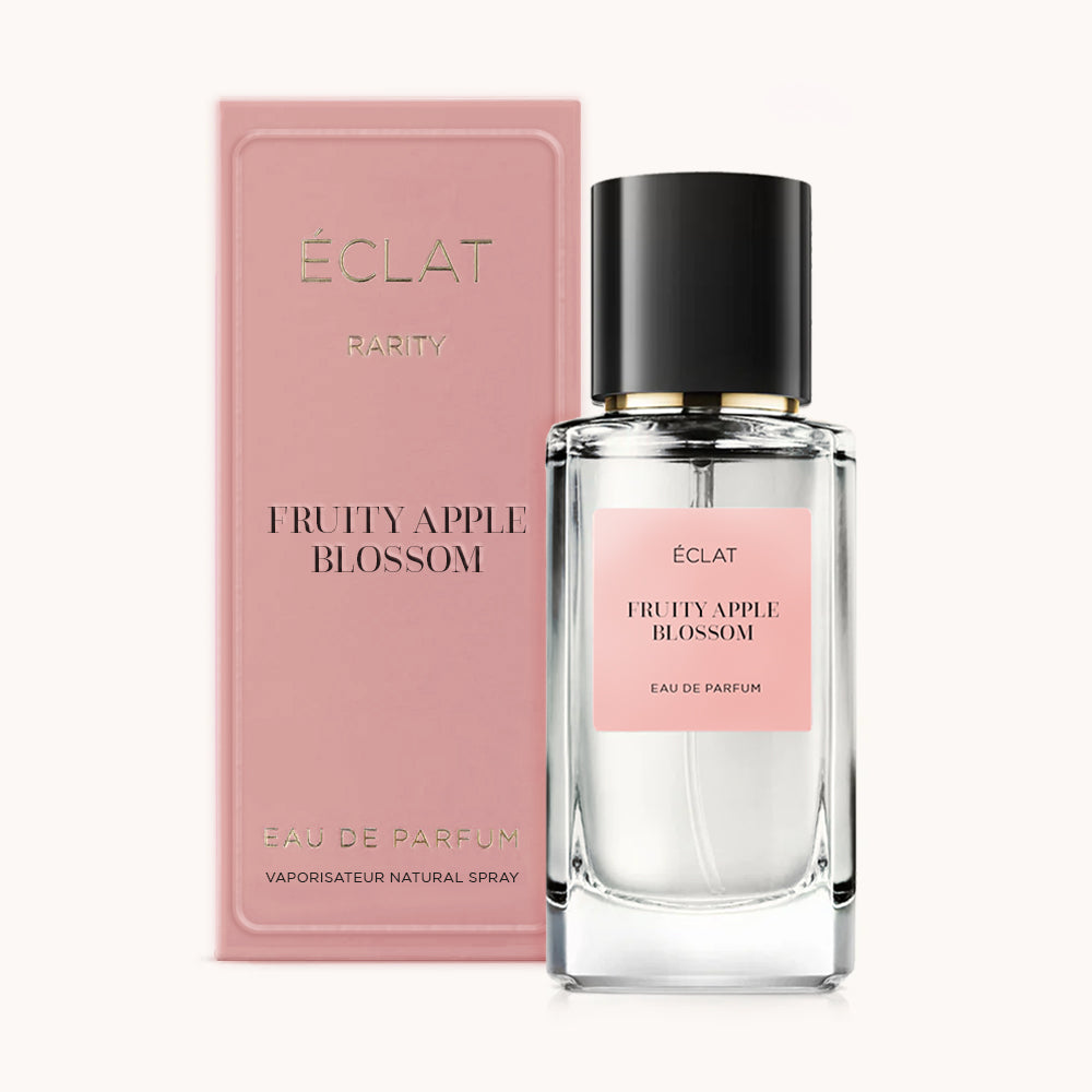 A faceted glass bottle with a pink label and a black cap, next to a matching pink box, displaying ÉCLAT Fruity Apple Blossom.