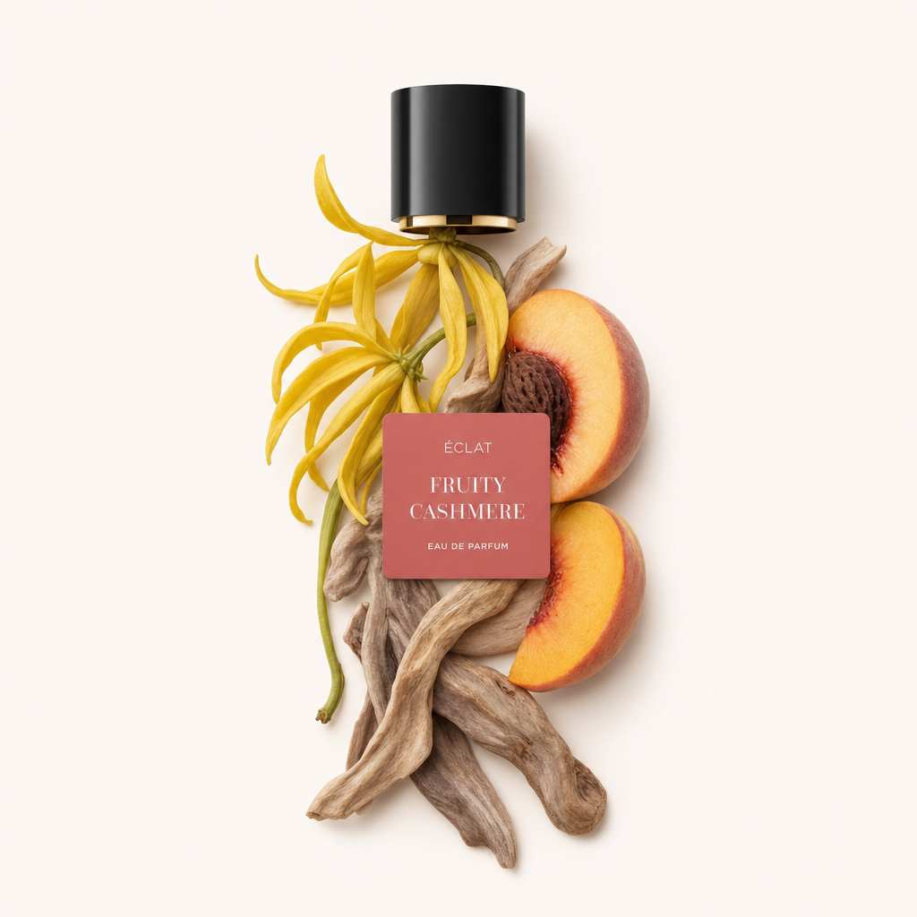 An arrangement of ylang-ylang flowers, peach halves, and sandalwood sticks with a black cap featuring an ÉCLAT Fruity Cashmere label.