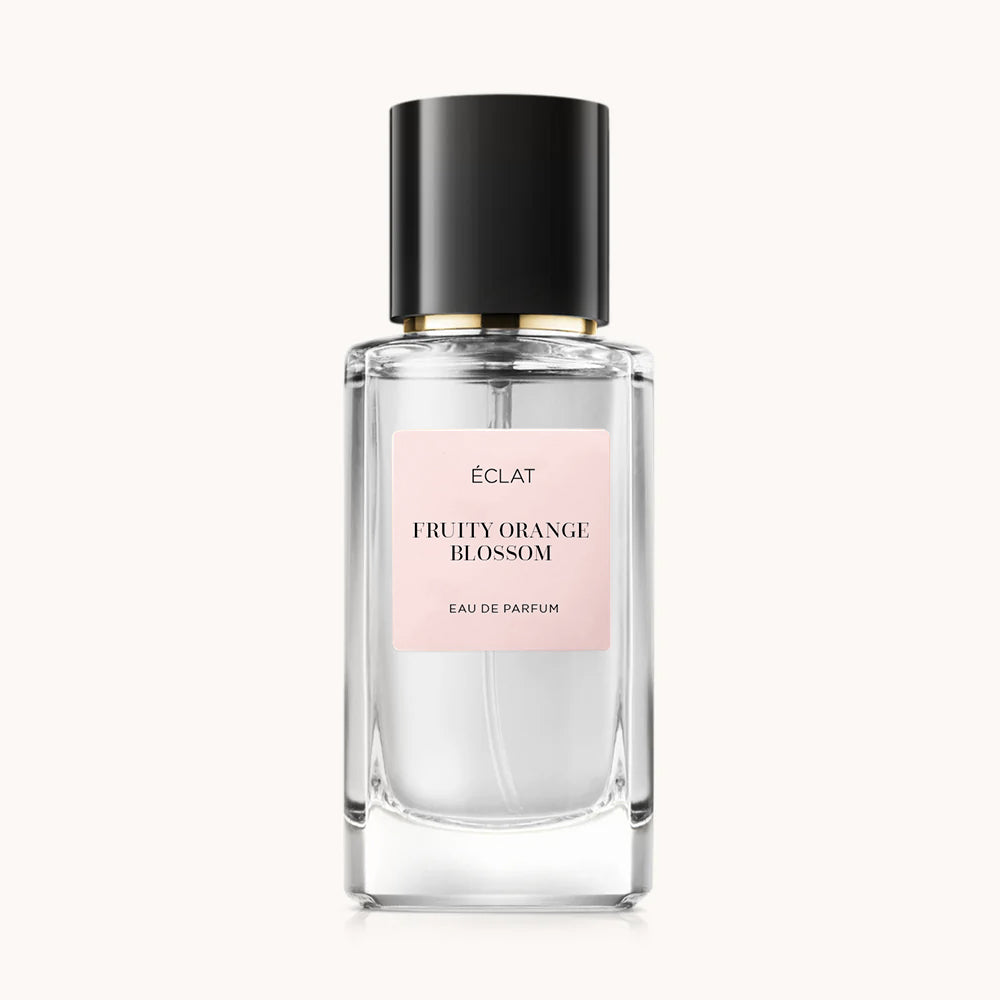 A faceted glass bottle with a black cap, featuring a pink label for ÉCLAT Fruity Orange Blossom.