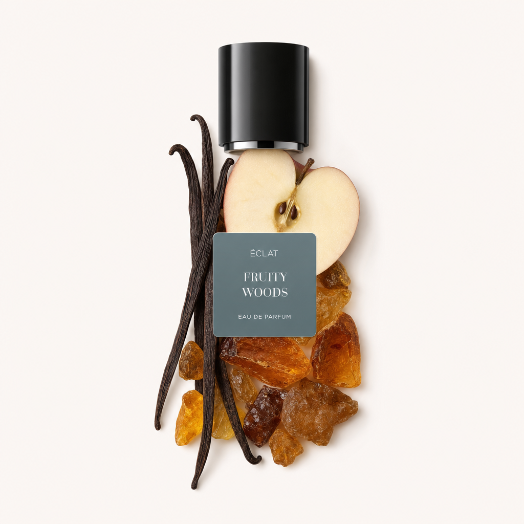 Ett arrangemang av en äppelskiva, vaniljbönor och hartser, toppat med en svart lock med ÉCLAT Fruity Woods-etiketten.