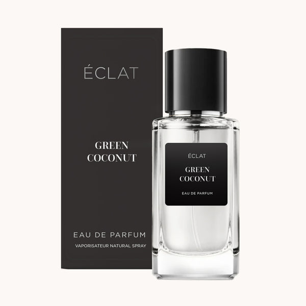 Fragancia ÉCLAT Green Coconut en un frasco de vidrio transparente con etiqueta y tapón negros, junto a su caja negra a juego.