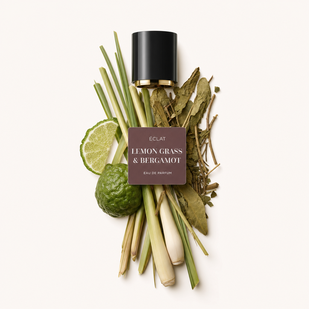 An arrangement of lemongrass stalks, kaffir lime leaves, sliced lime, and whole bergamot fruit, alongside a black cap with label of ÉCLAT Lemon Grass & Bergamot.