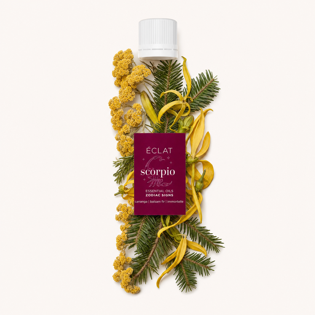 Sárga ylang-ylang virágok, sárga örökzöld virágok és zöld fenyőágak kompozíciója körülvesz egy fekete kupakot az ÉCLAT Scorpio csillagjegyű illóolajainak címkéjével.
