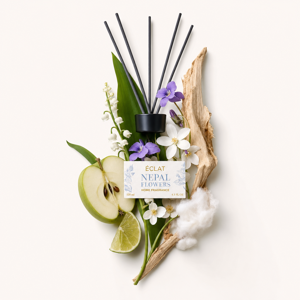 A Nepal Flowers illat hozzávalóinak elrendezése friss almaszeletekkel, lime-mal, gyöngyvirággal, ibolyákkal és fával, fekete kupakkal címkével kísérve.