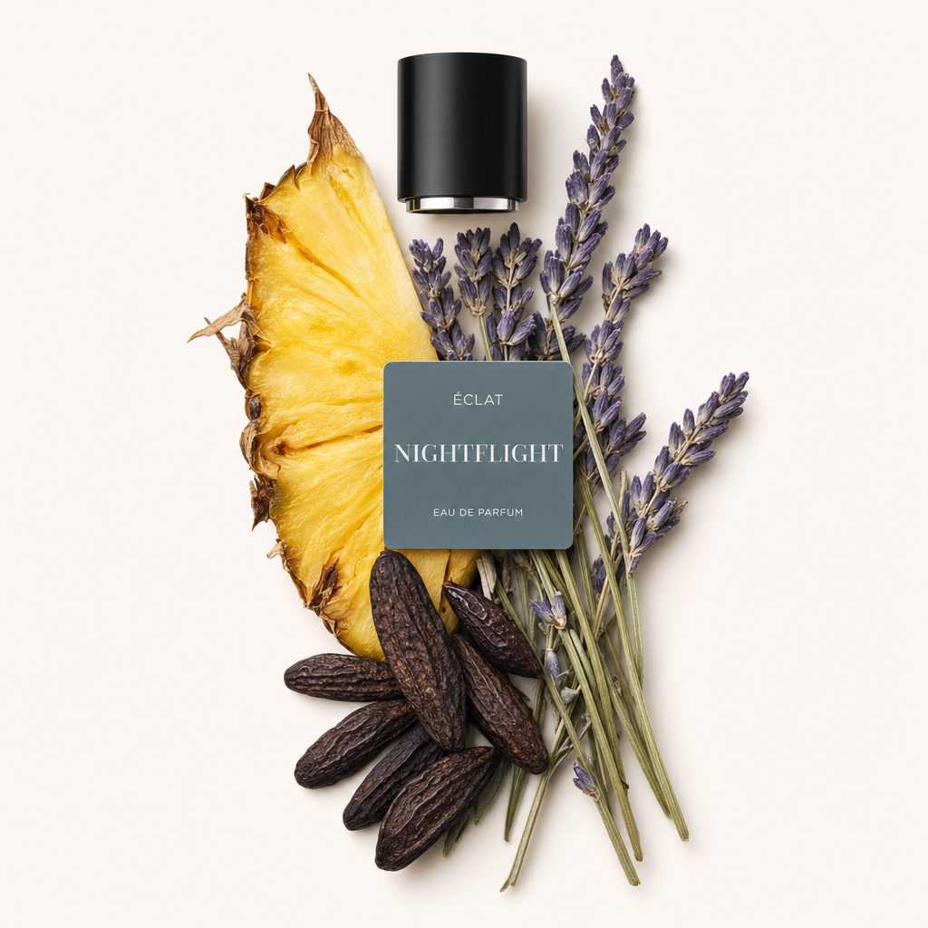 An arrangement of pineapple slice, lavender sprigs, and tonka beans beneath a black cap with label for ÉCLAT Nightflight.