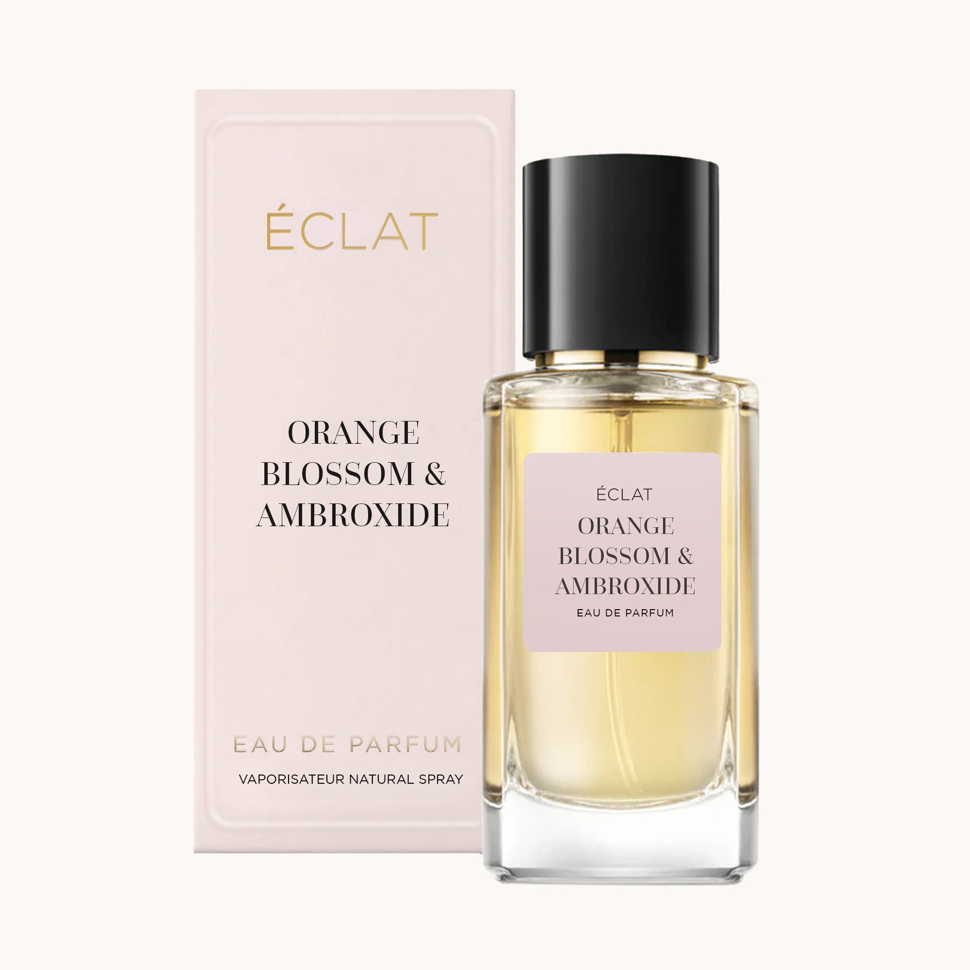 Elegant ÉCLAT Orange Blossom & Ambroxide perfume with a faceted glass bottle and black cap, accompanied by a pastel pink box.