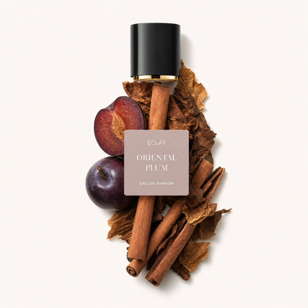 Um arranjo de paus de canela, folhas de tabaco secas e ameixas maduras rodeia uma tampa preta com detalhes dourados etiquetada ÉCLAT Oriental Plum.