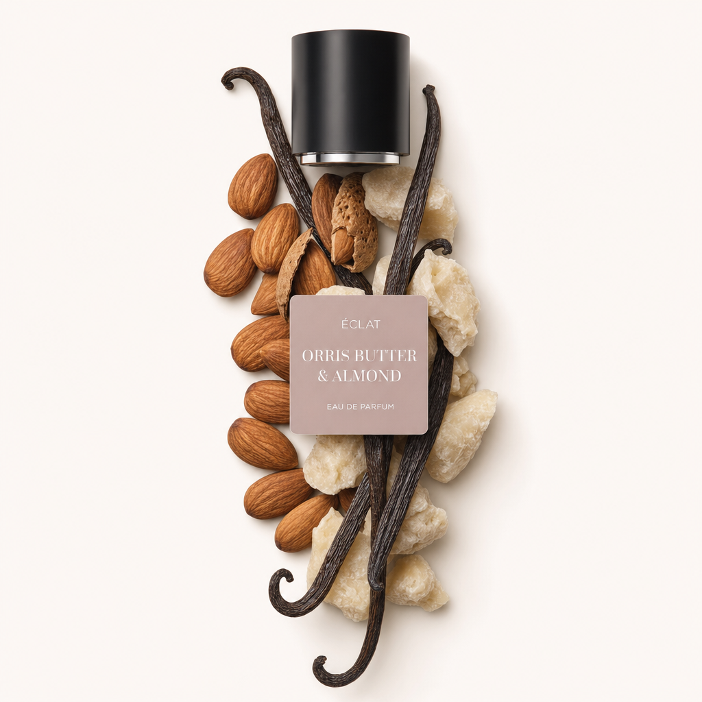 Un arrangement d'amandes, de gousses de vanille et de morceaux de beurre d'iris entoure un bouchon noir avec une étiquette pour ÉCLAT Orris Butter & Almond.