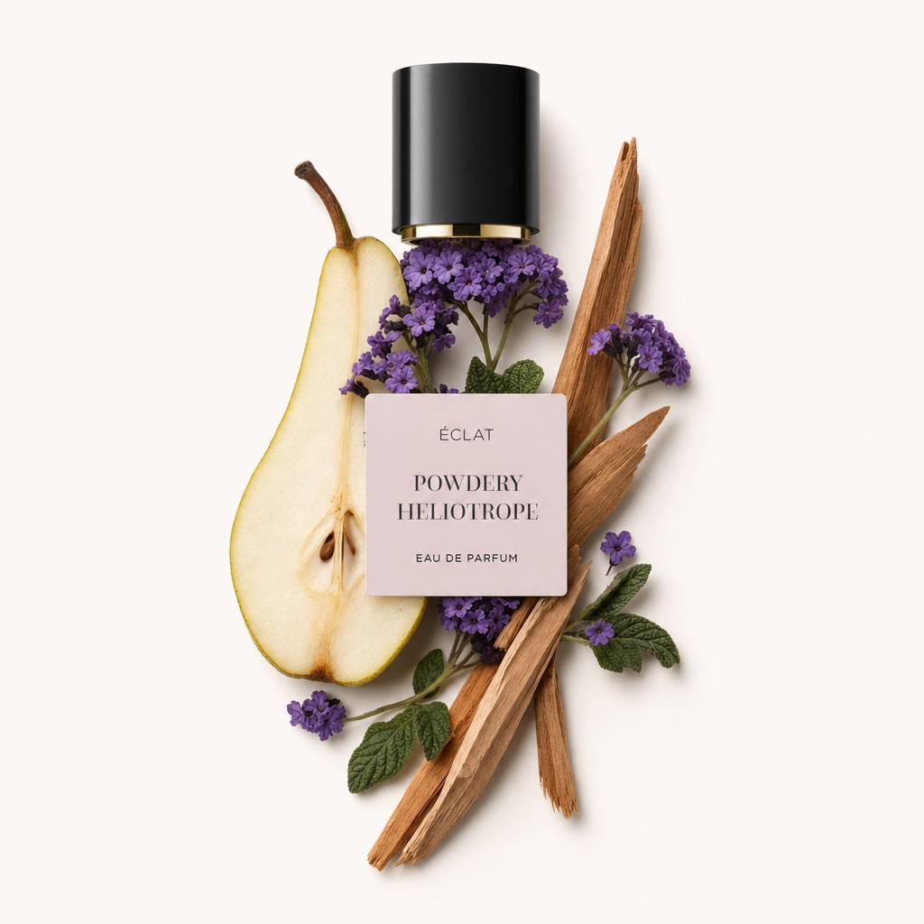 Un arrangement de fleurs de héliotrope violettes, une poire tranchée, des feuilles vertes et des bâtons de bois entoure un capuchon noir avec étiquette pour ÉCLAT Powdery Heliotrope.