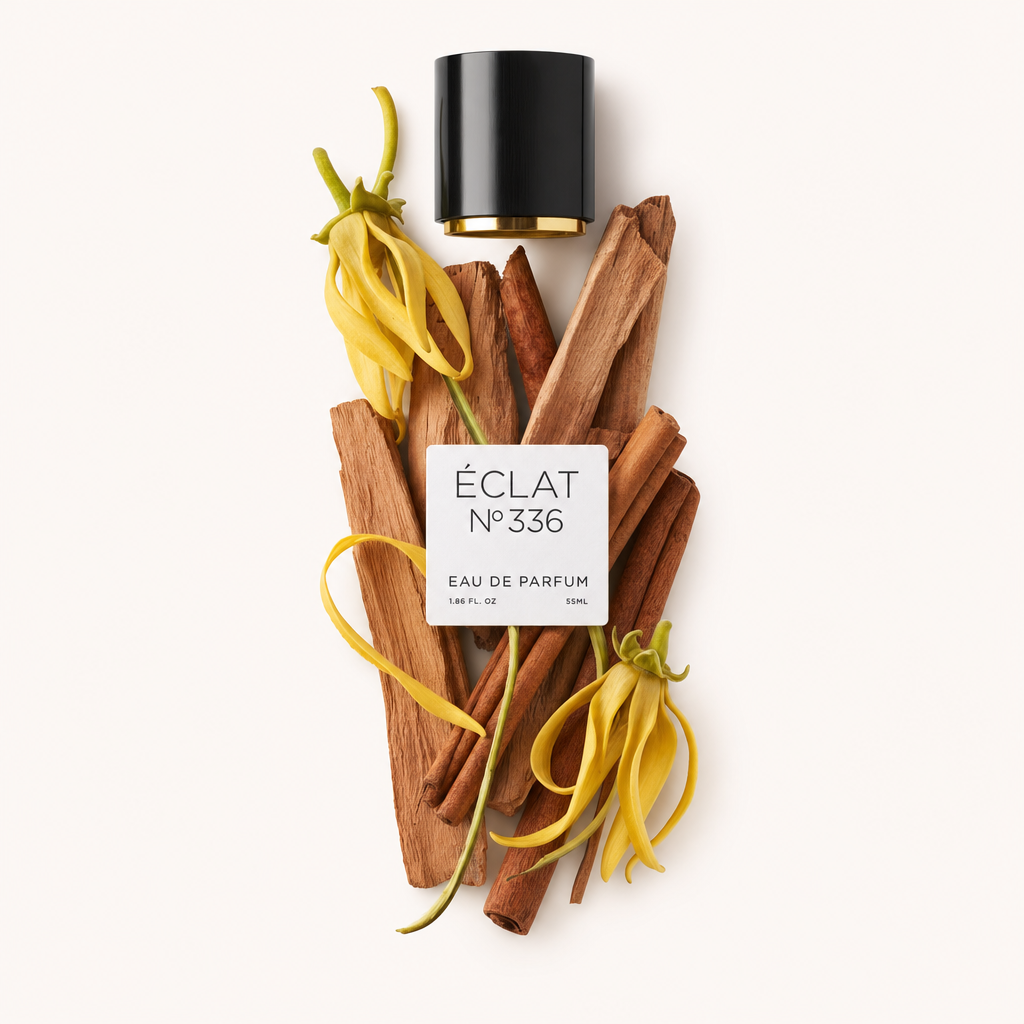 Een arrangement van gele ylang-ylang bloemen en sandelhoutstokjes begeleidt een zwarte dop met etiket voor ÉCLAT Powdery Sandalwood.