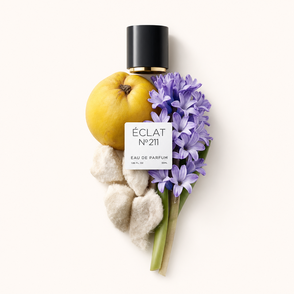 Un arrangement de coing, jacinthes violettes et éléments doux entoure un bouchon noir avec une étiquette ÉCLAT.