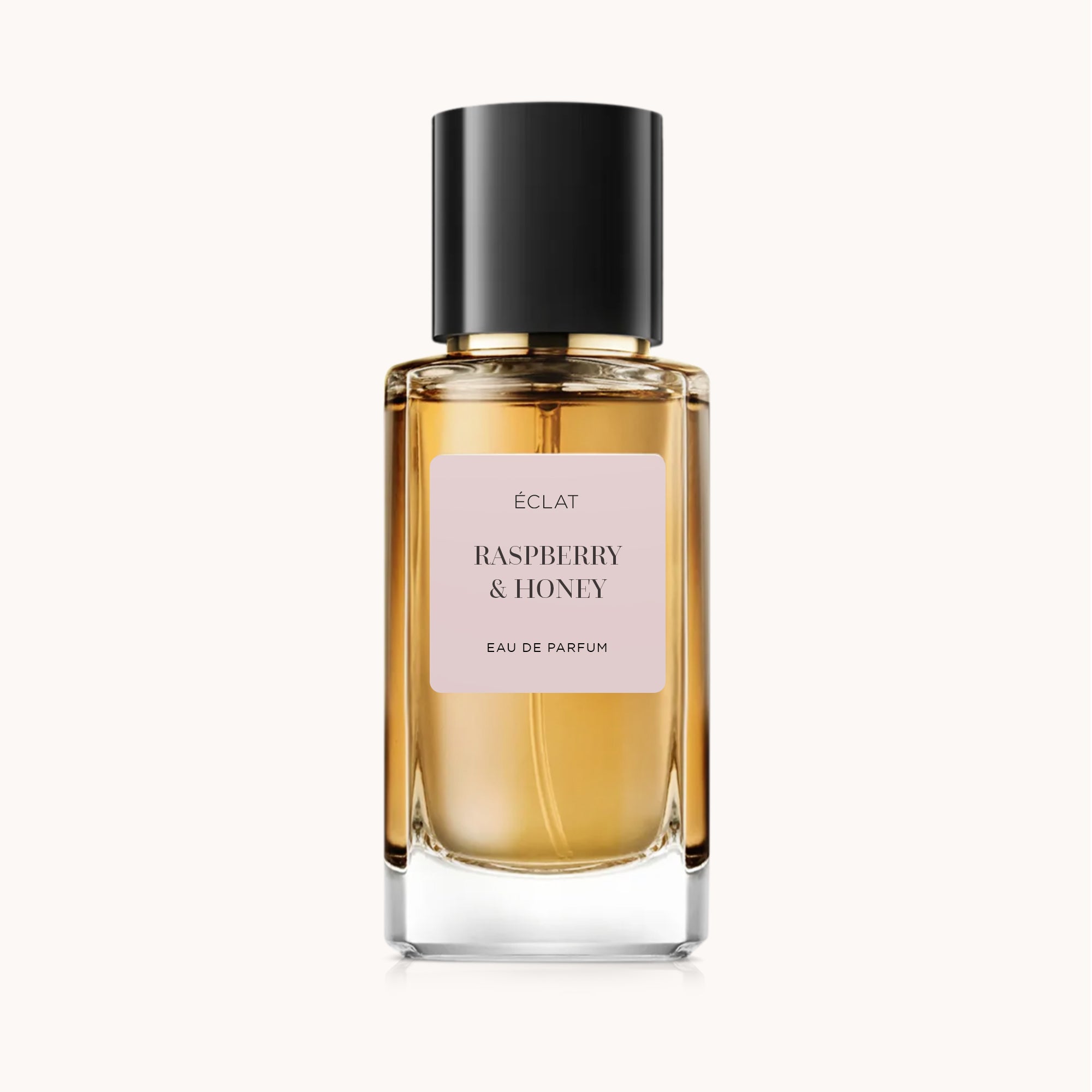 A faceted glass bottle of ÉCLAT Raspberry & Honey perfume with a matte label and a black cap.