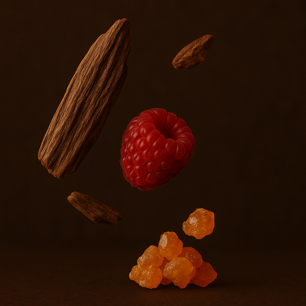 Floating pieces of oud wood, a red raspberry, and amber resin on a deep brown background, highlighting the essence of ÉCLAT Resinous Oud.