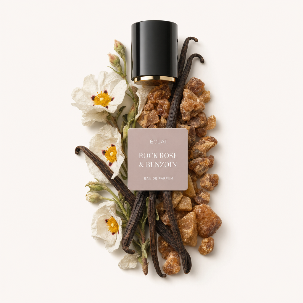 Un arrangement de gousses de vanille, de fleurs de ciste et de résine de benjoin entoure un capuchon noir à bord doré portant l'étiquette ÉCLAT Rock Rose & Benzoin.