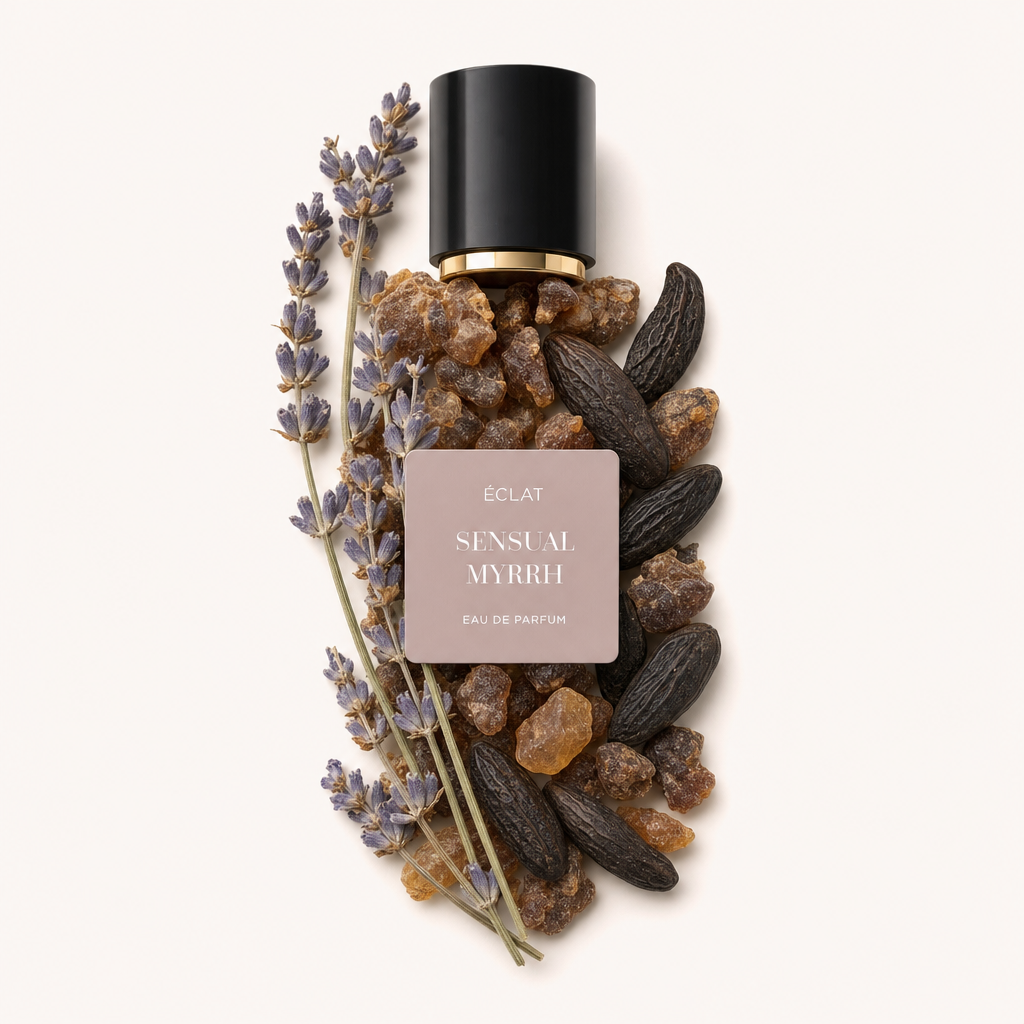 Un arrangement de brins de lavande, de résine de myrrhe et de fèves tonka entoure un capuchon noir à bord doré avec une étiquette ÉCLAT Sensual Myrrh.
