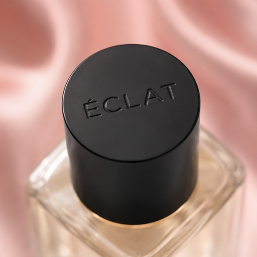 ÉCLAT Silk & Cashmere in a faceted glass bottle with a matte black cap on a pink satin background.