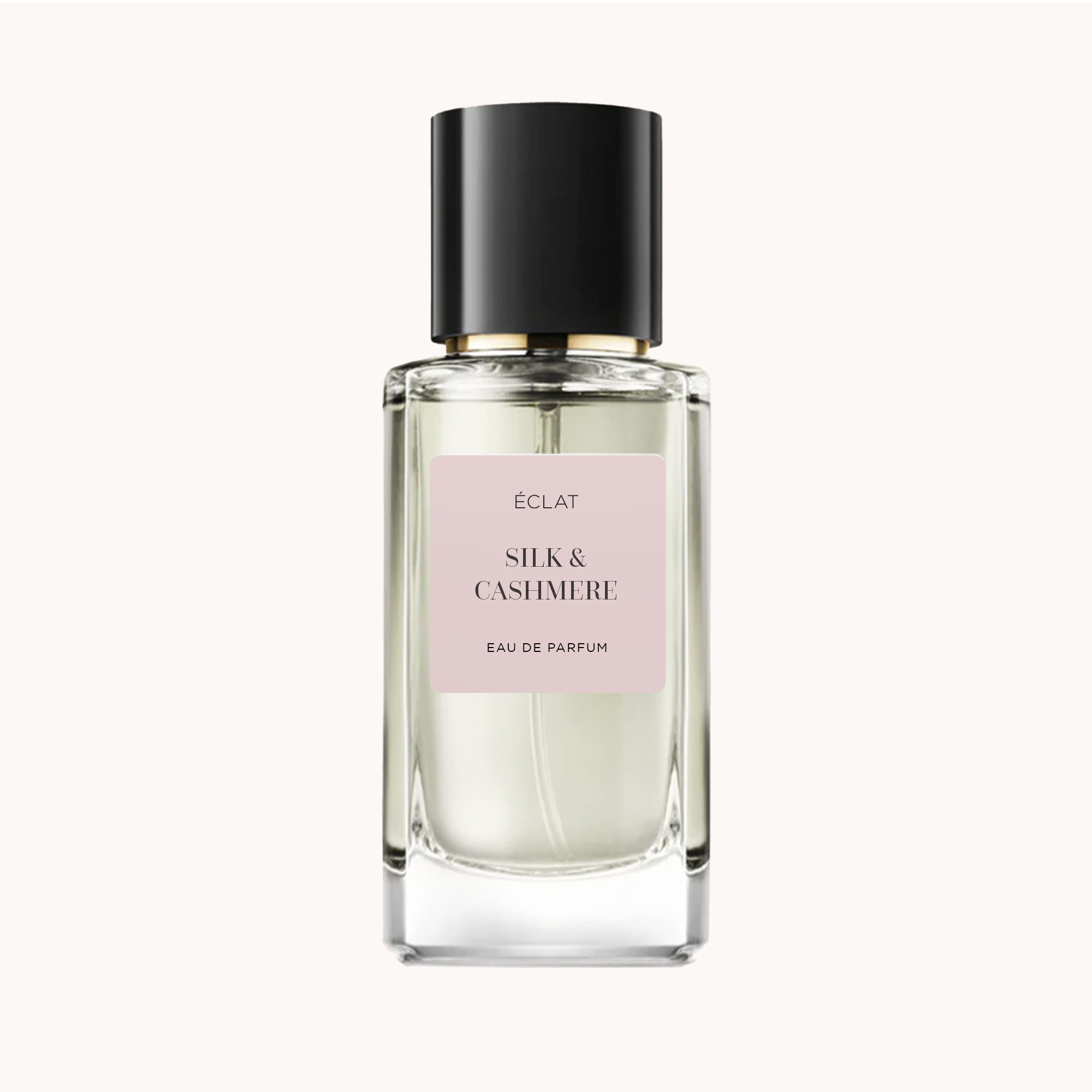 Faceted glass bottle with a matte black cap and a light pink label displaying ÉCLAT Silk & Cashmere.