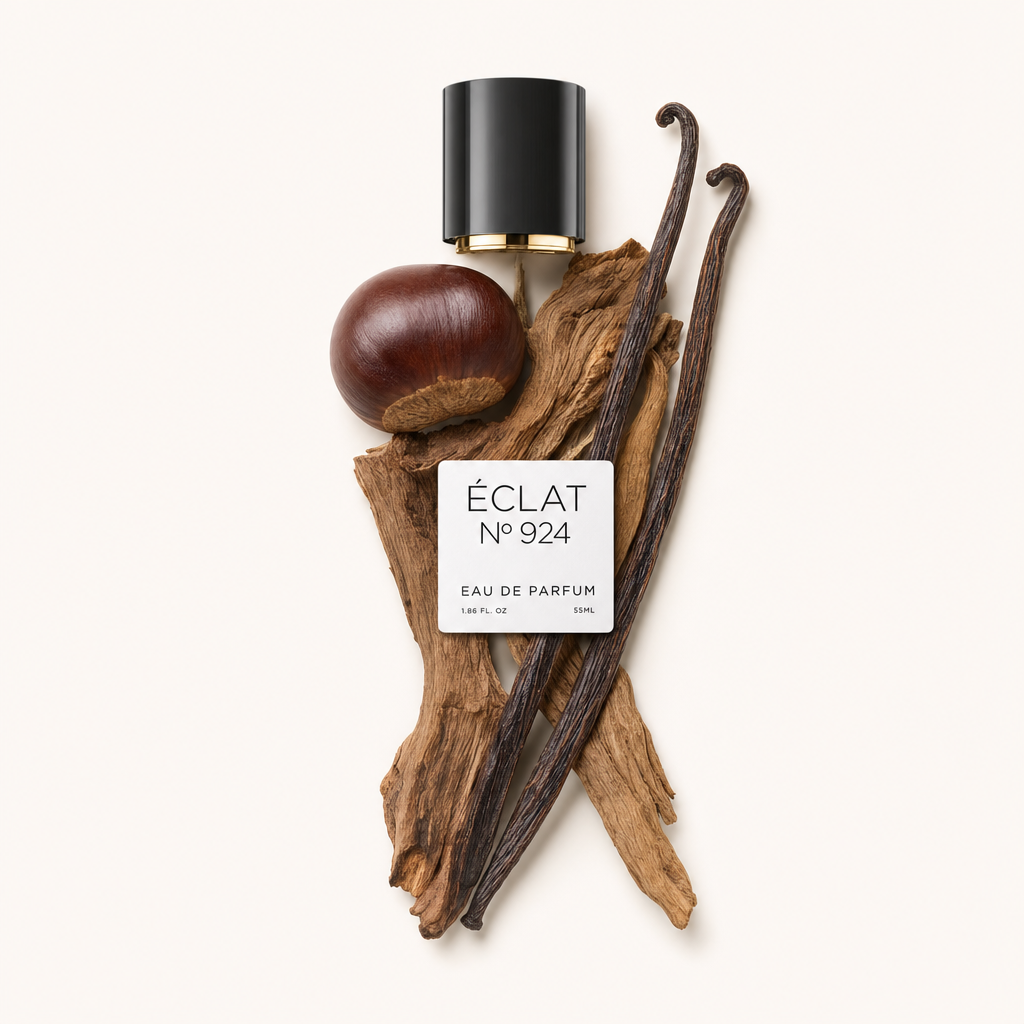 Une composition artistique du ÉCLAT Smoky Chestnut comprend un capuchon noir brillant avec un accent doré, une châtaigne entière, des gousses de vanille parfumées et des éléments de bois texturés.