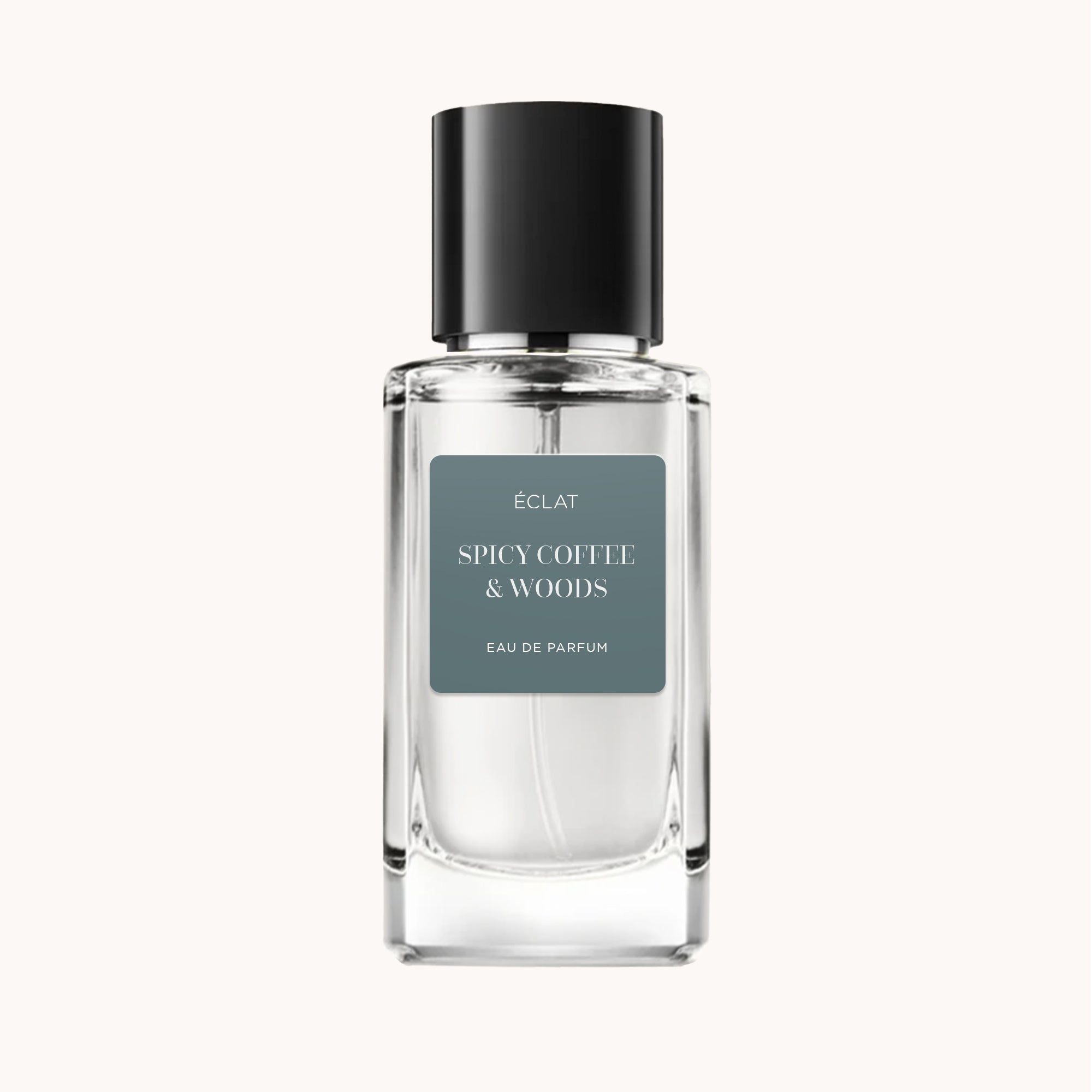 The ÉCLAT Spicy Coffee & Woods perfume bottle features a clear faceted glass with a black cap and a matte grey label.