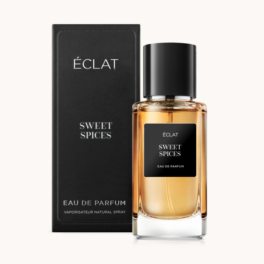 Fragrância ÉCLAT Sweet Spices em um elegante frasco de vidro com tampa e rótulo pretos, acompanhado por uma caixa preta correspondente.